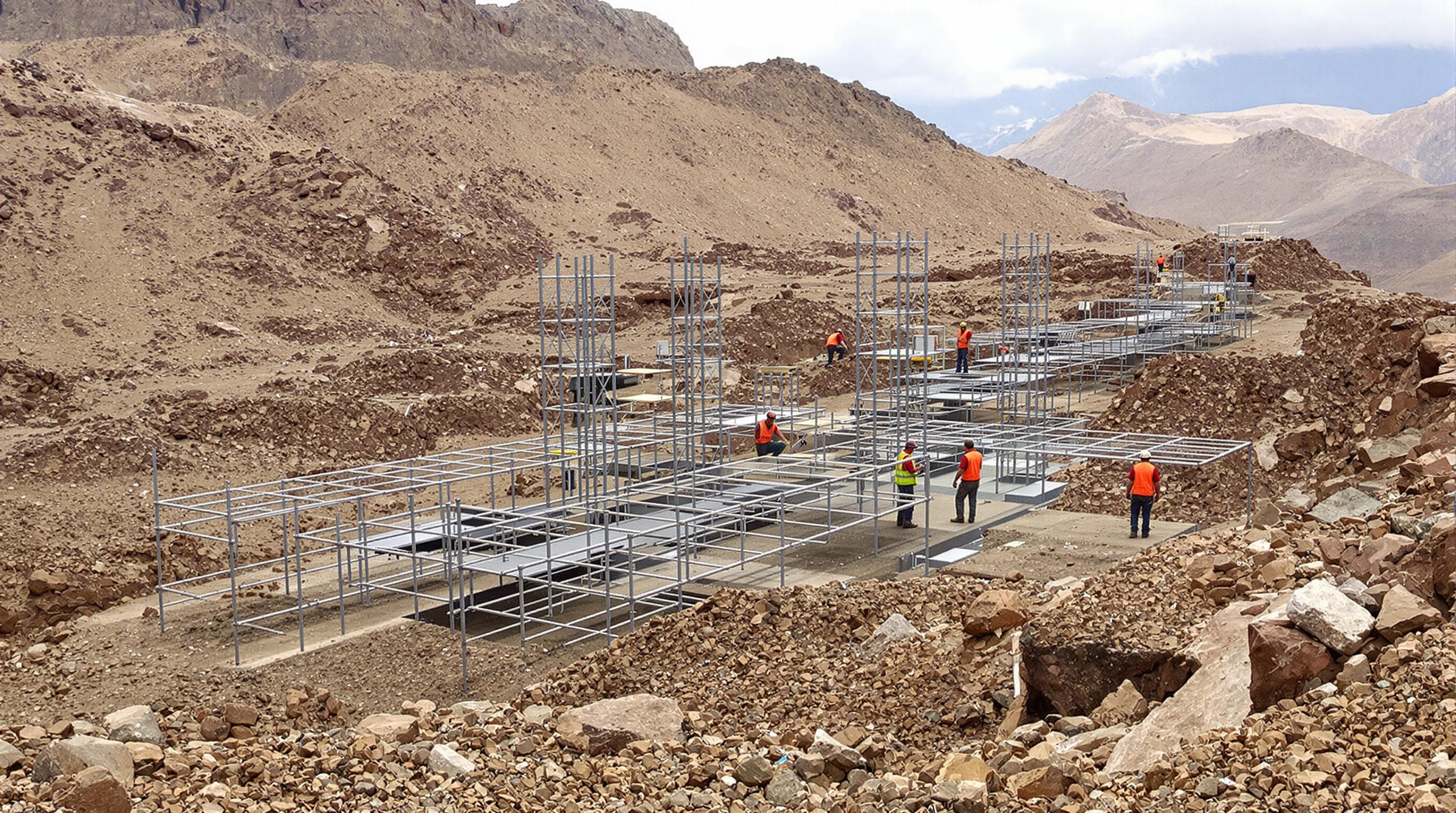 Engineers inspecting modular steel and polymer obstacles on an endurance racing course integrated into natural terrain