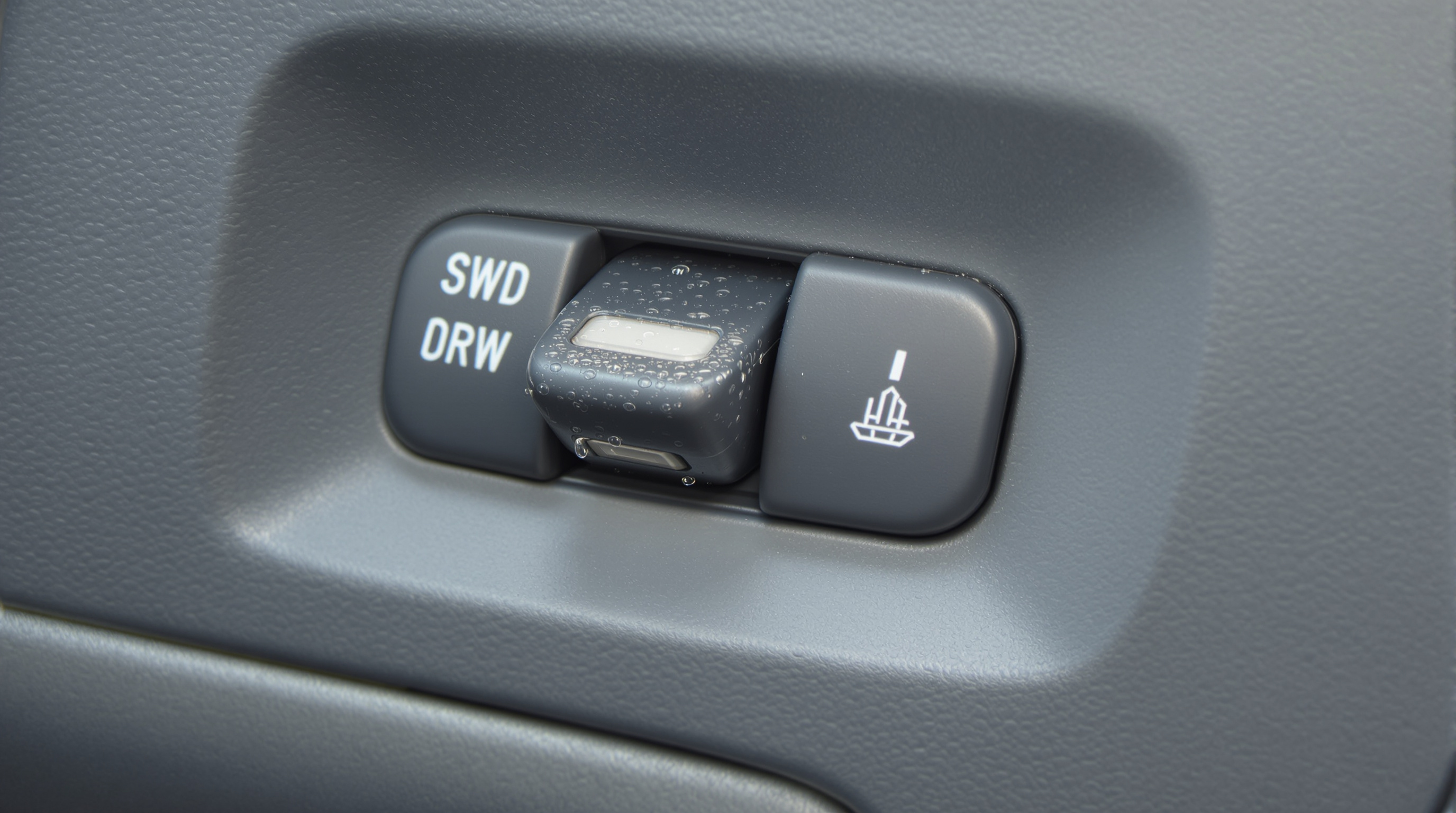 Close-up realistic photo of an automotive rocker switch on a dashboard with hints of moisture and sealed housing