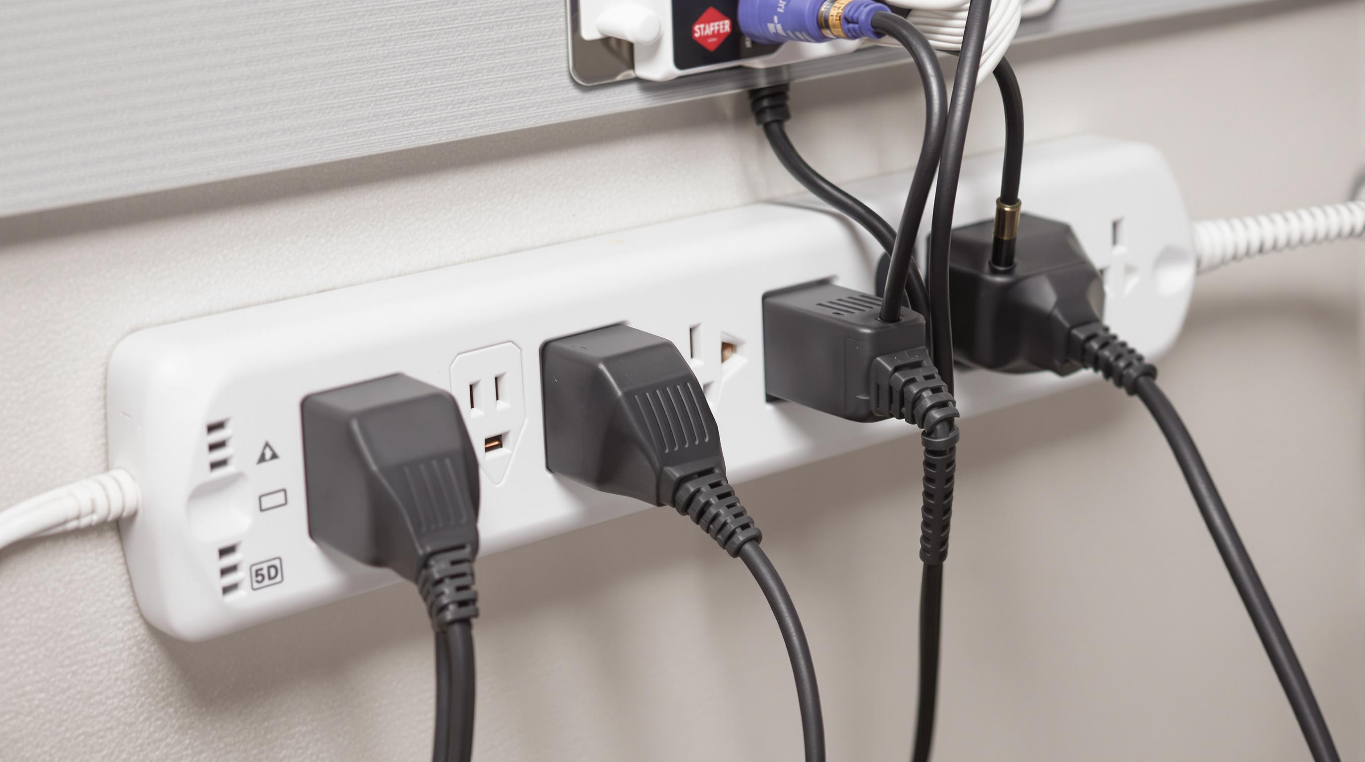 Adapters plugged into a surge protector with thick cables in a muted color office setup
