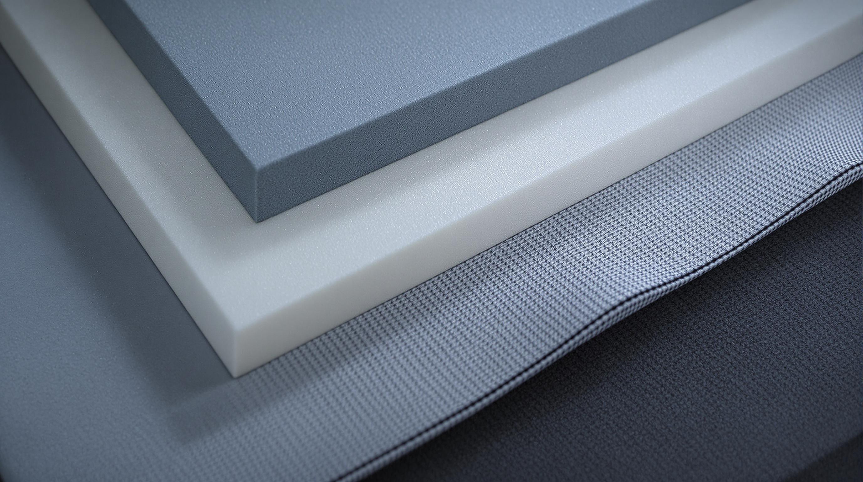 Close-up photo of different back protector materials including polymer foams, composite fibers, and moisture-wicking fabrics on a grey lab table