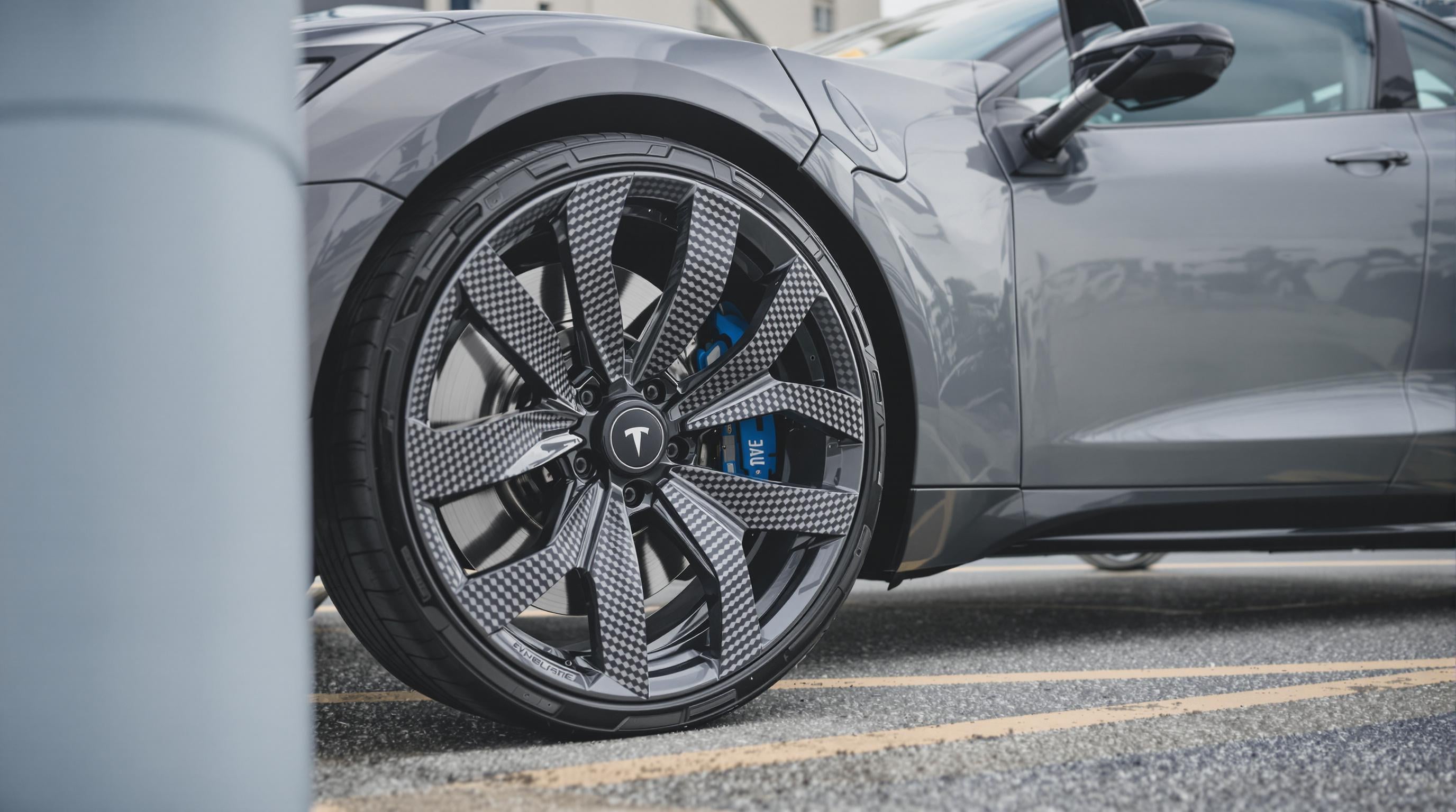 Electric vehicle at a charging station highlighting its carbon fiber wheels in an urban setting