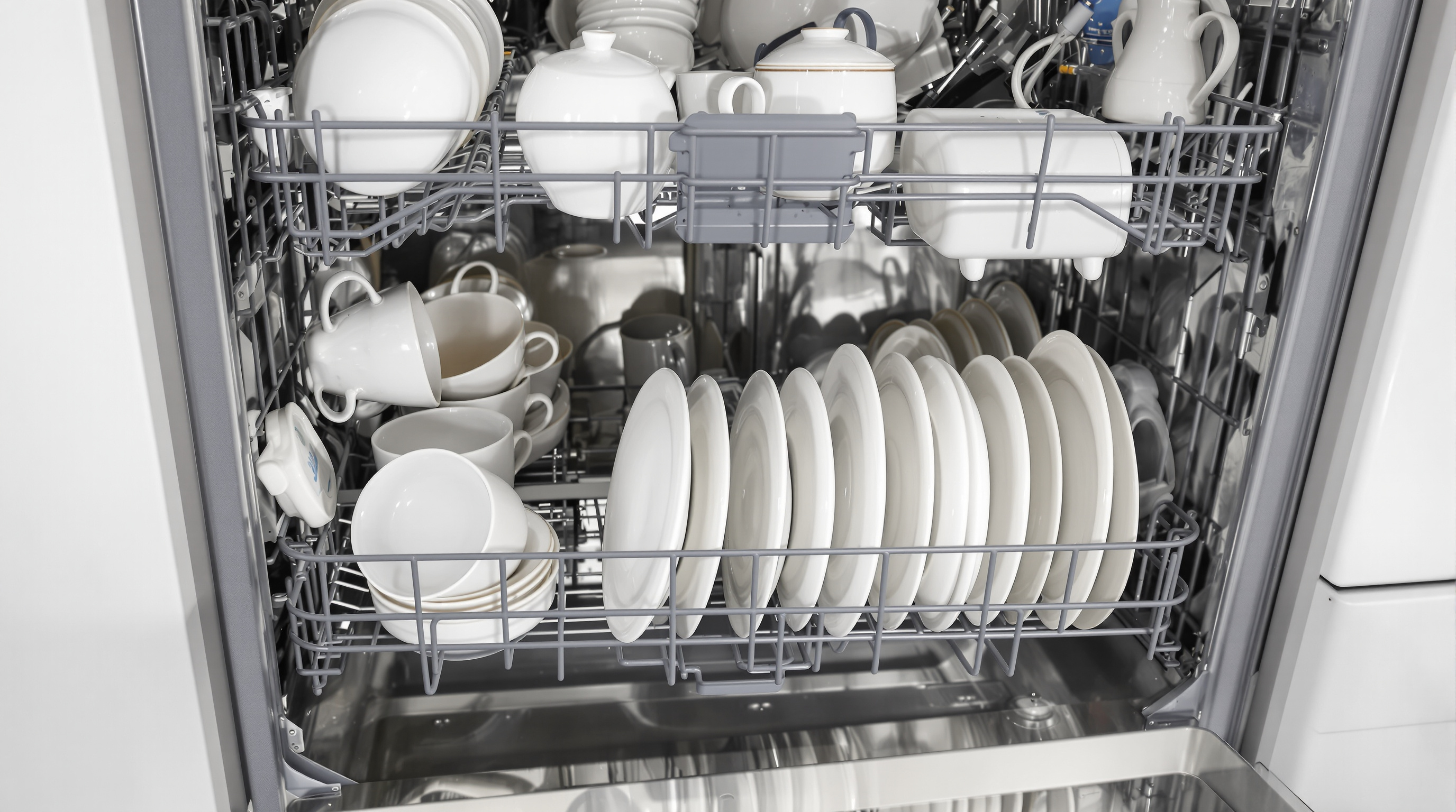 Fine porcelain dishes properly loaded and spaced in an open dishwasher with soft lighting