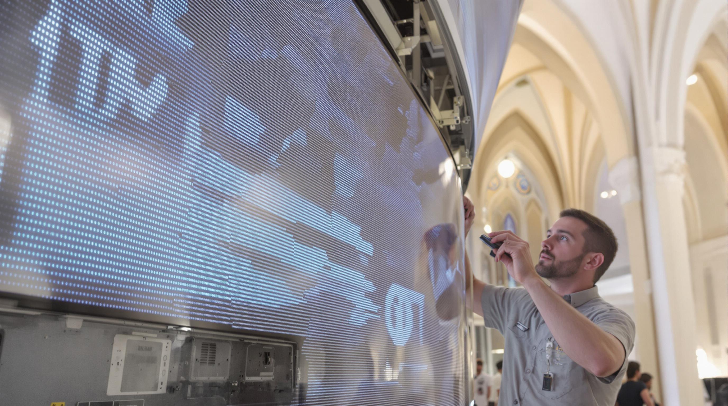 Technician working on seamless curved LED screen installation with visible electronics in a museum setting
