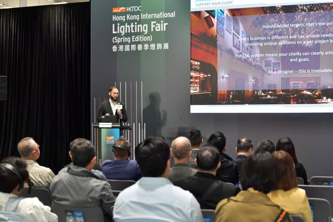 Speaker at HKTDC Hong Kong International Lighting Fair presenting 'SUPPORT YOUR CLIENT' strategies, with presentation slides emphasizing individualized ESG solutions and project-based aluminum profile customization for lighting designers.
