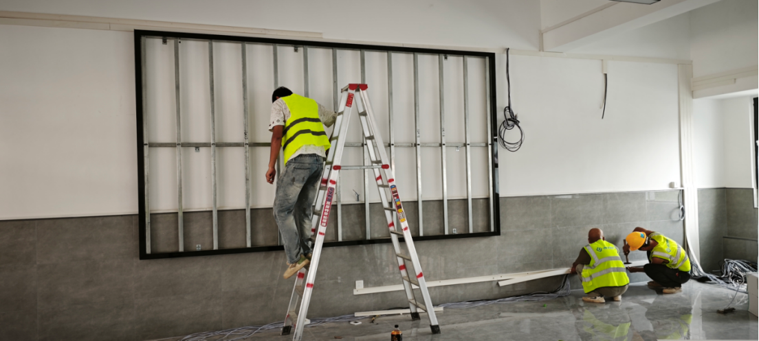 Technicians constructing a precision steel mounting frame on a wall for a seamless fine pitch indoor LED video wall installation