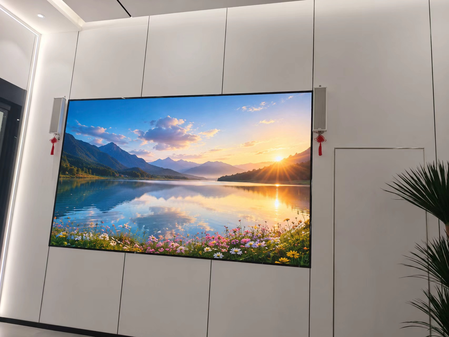 A large fine-pitch LED screen mounted on a modern paneled wall in a conference room, showing a crisp mountain and lake landscape.