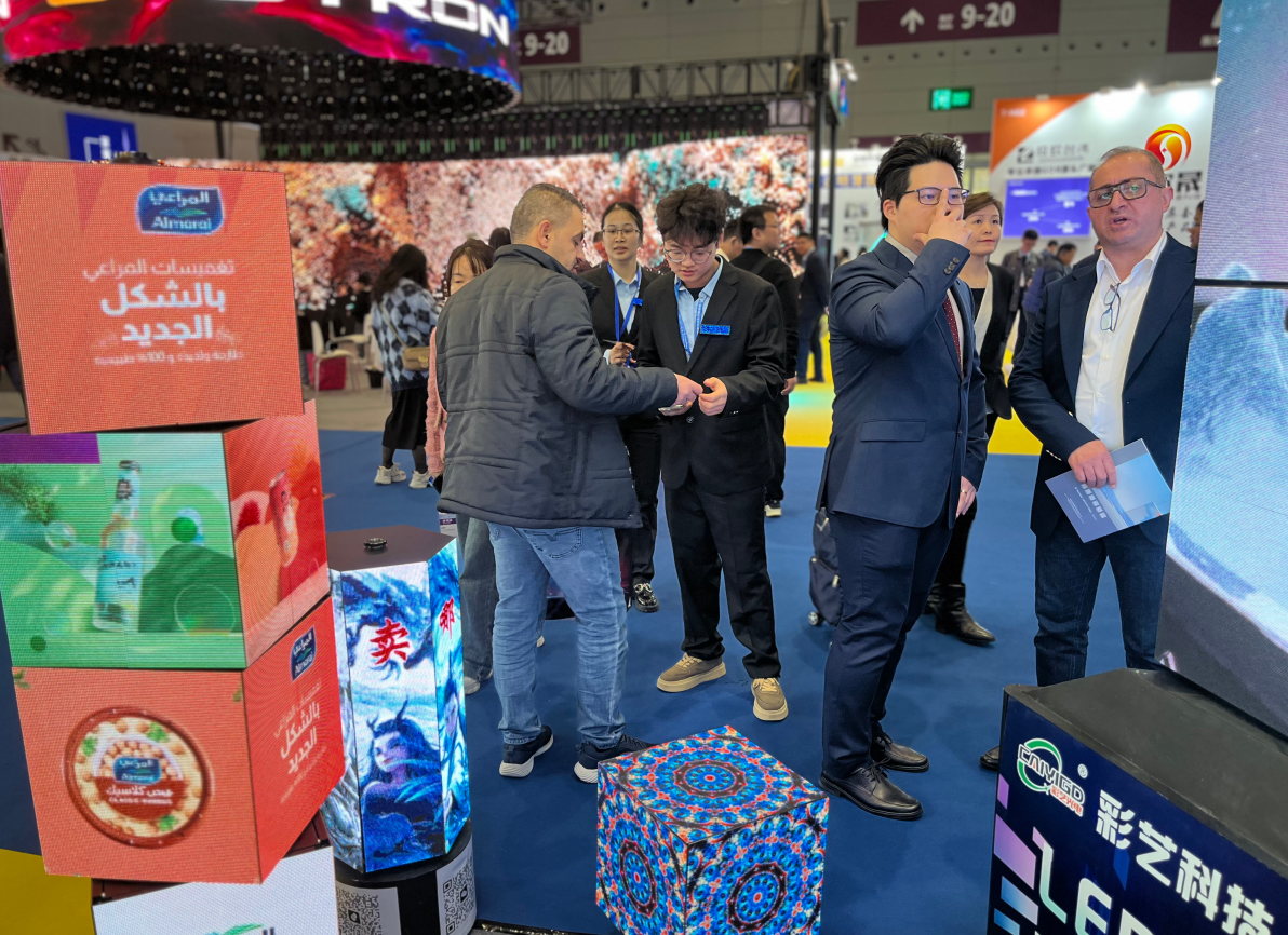 Sales representatives engaging with potential clients and generating B2B leads next to an eye-catching custom stacked cube LED display at a crowded exhibition