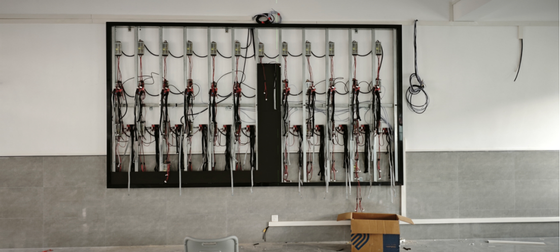 Colorartled engineer on a ladder installing power supplies and executing precision cable management for a front-service LED display structure.
