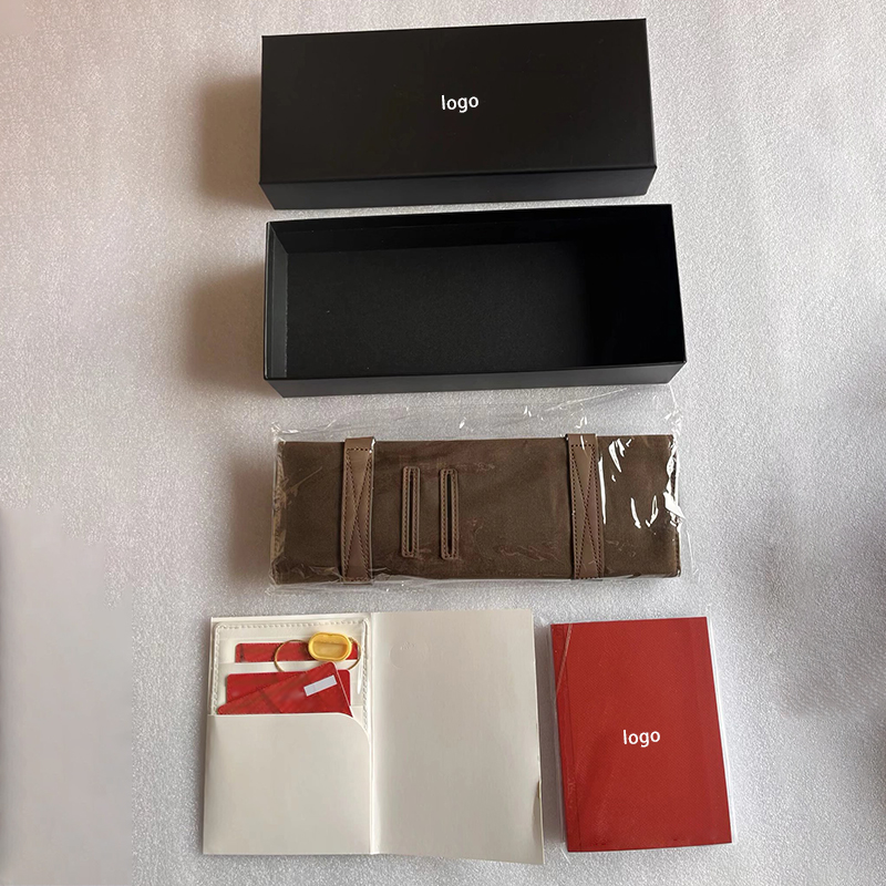 Top view of separated packaging components empty black box, plastic wrapped watch roll and accessory cards.jpg