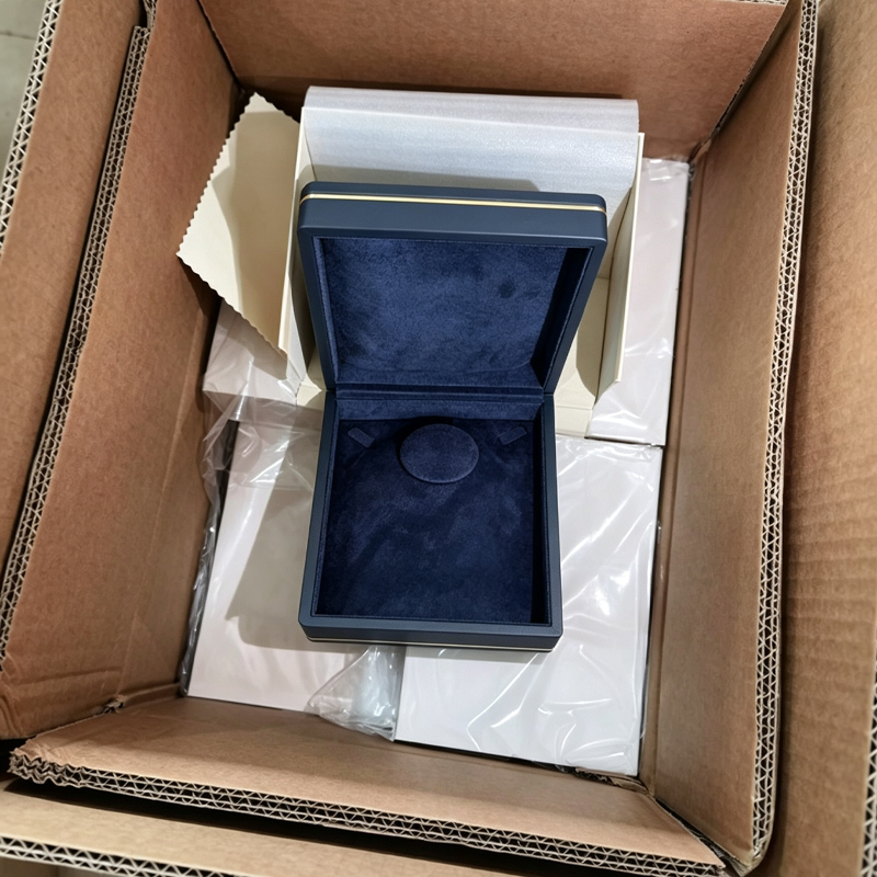 Open brown export carton with the jewelry box cushion-wrapped in paper and clear film inside.jpg