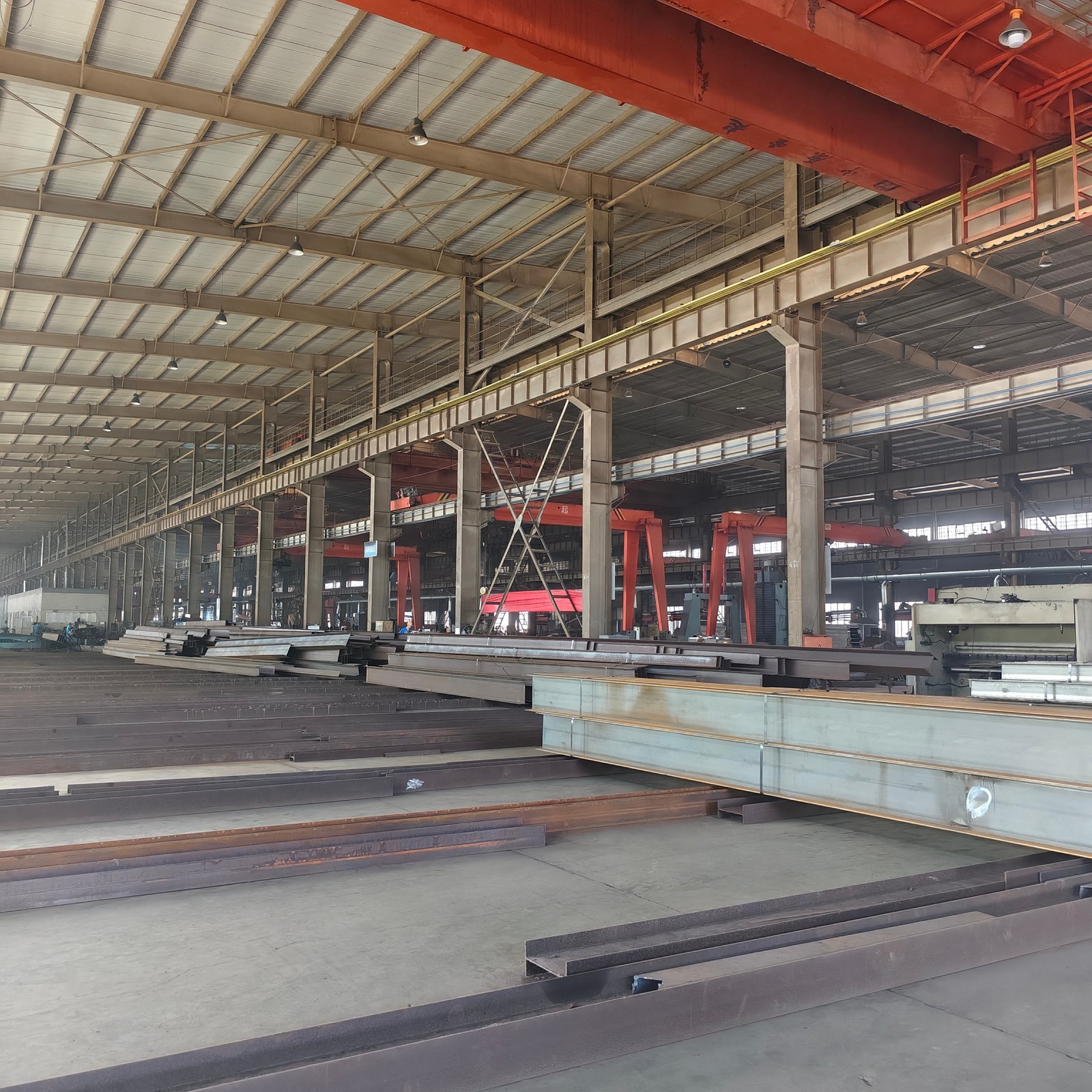 Stacked H-beams and steel structure members in a high-bay workshop