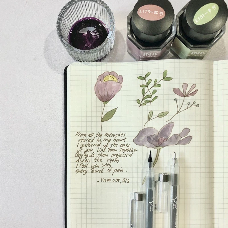 Poezie Glass Ink Bottle on Desk with Shimmering Calligraphy Art Piece