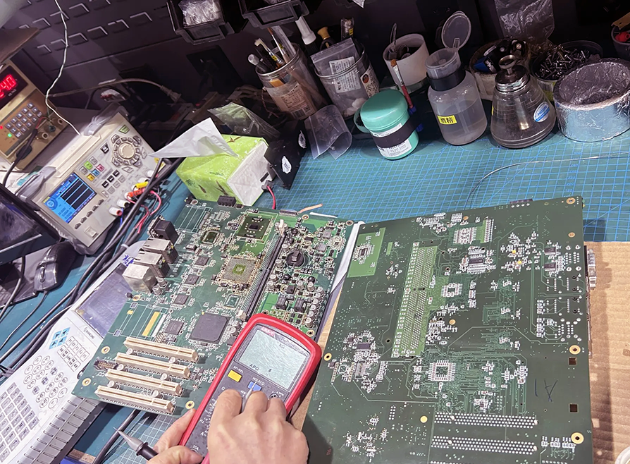 Robot controller board repair on the bench — a board under test with a multimeter