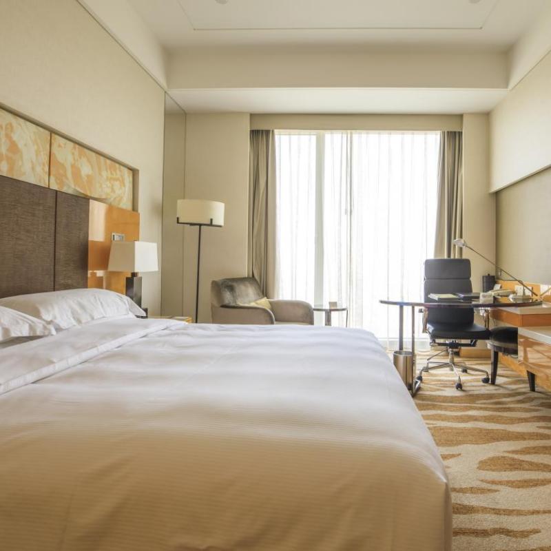 Fully furnished luxury hotel guest room prepared with crisp linens and working desk, demonstrating complete product procurement before grand opening.jpg