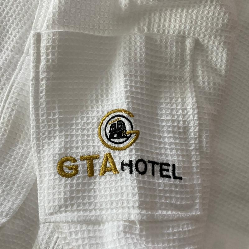 White waffle-weave hotel bathrobe pocket with customized gold and black GTA HOTEL logo embroidery.JPG
