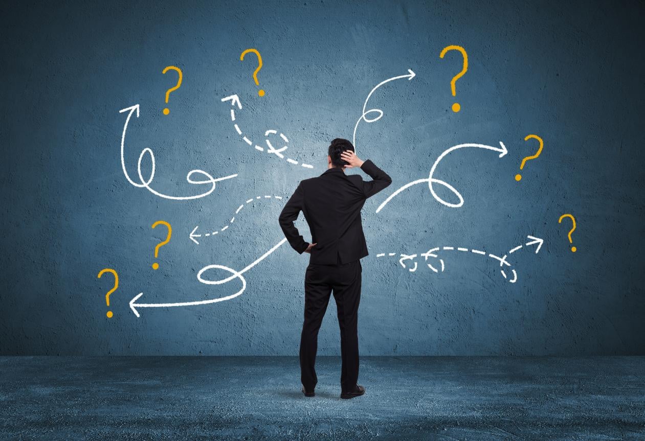 A hotel manager in a suit facing a dark wall with glowing question marks and tangled arrows, representing the complexity and confusion of decentralized hotel procurement and opening delays.
