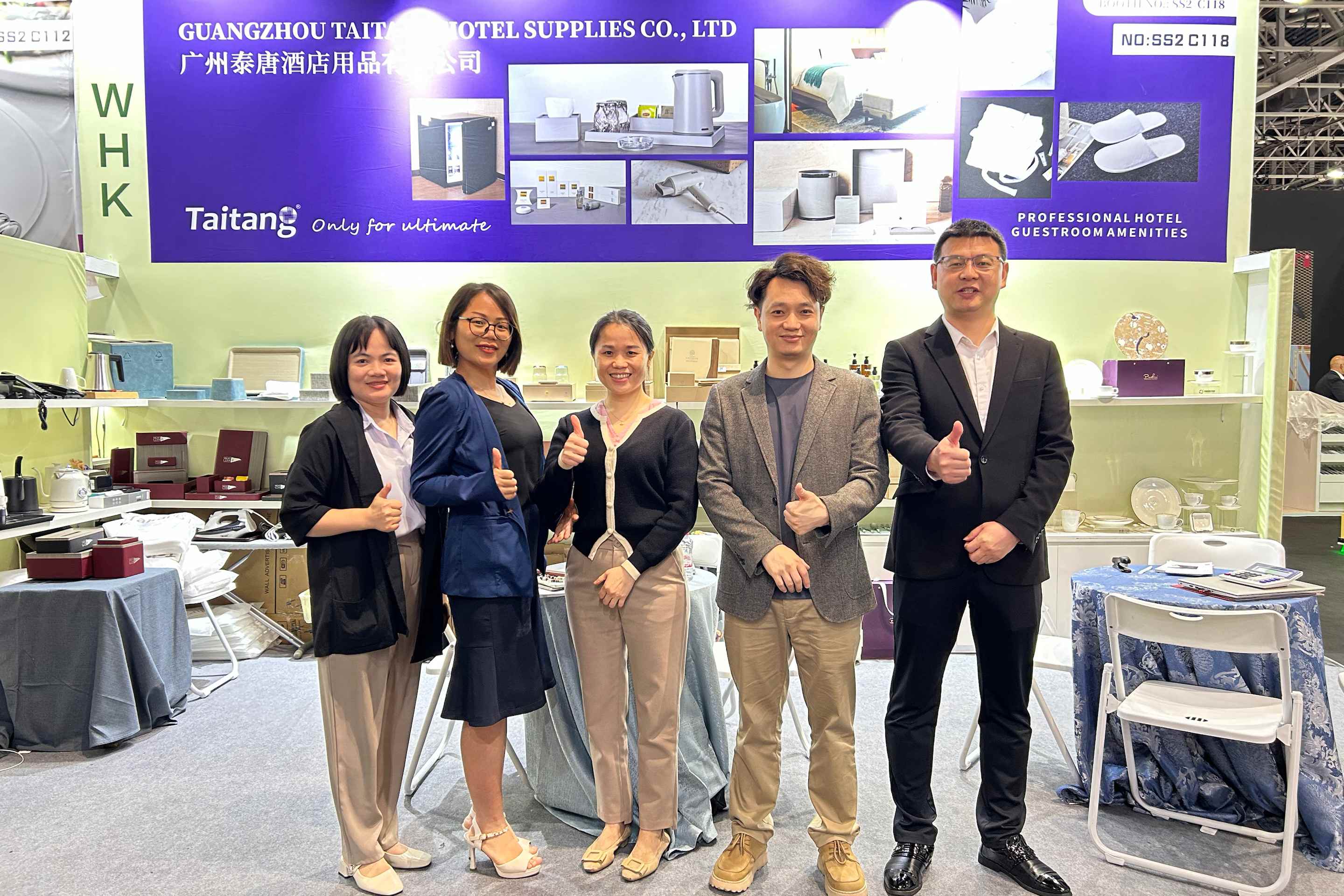 The TAITANG professional service team giving a thumbs-up at their exhibition booth, symbolizing their commitment to 