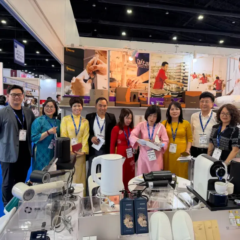 A group of people posing together at a trade show booth in Thailand, which is stocked with home goods and appliances.webp