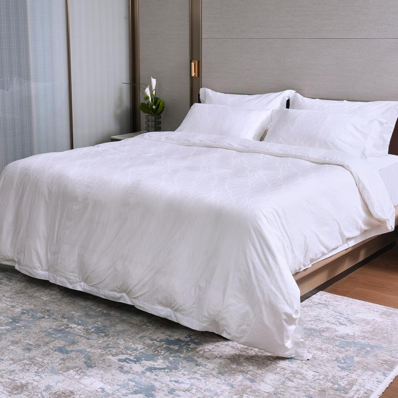 Taitang white hotel duvet insert with subtle wave textured pattern dressed on a hotel bed.jpg