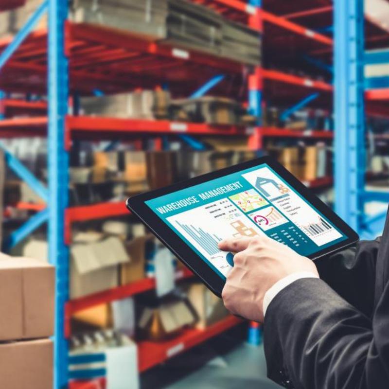 Procurement manager checking inventory management dashboard on tablet in a organized warehouse, demonstrating Taitang efficient logistics network.jpg