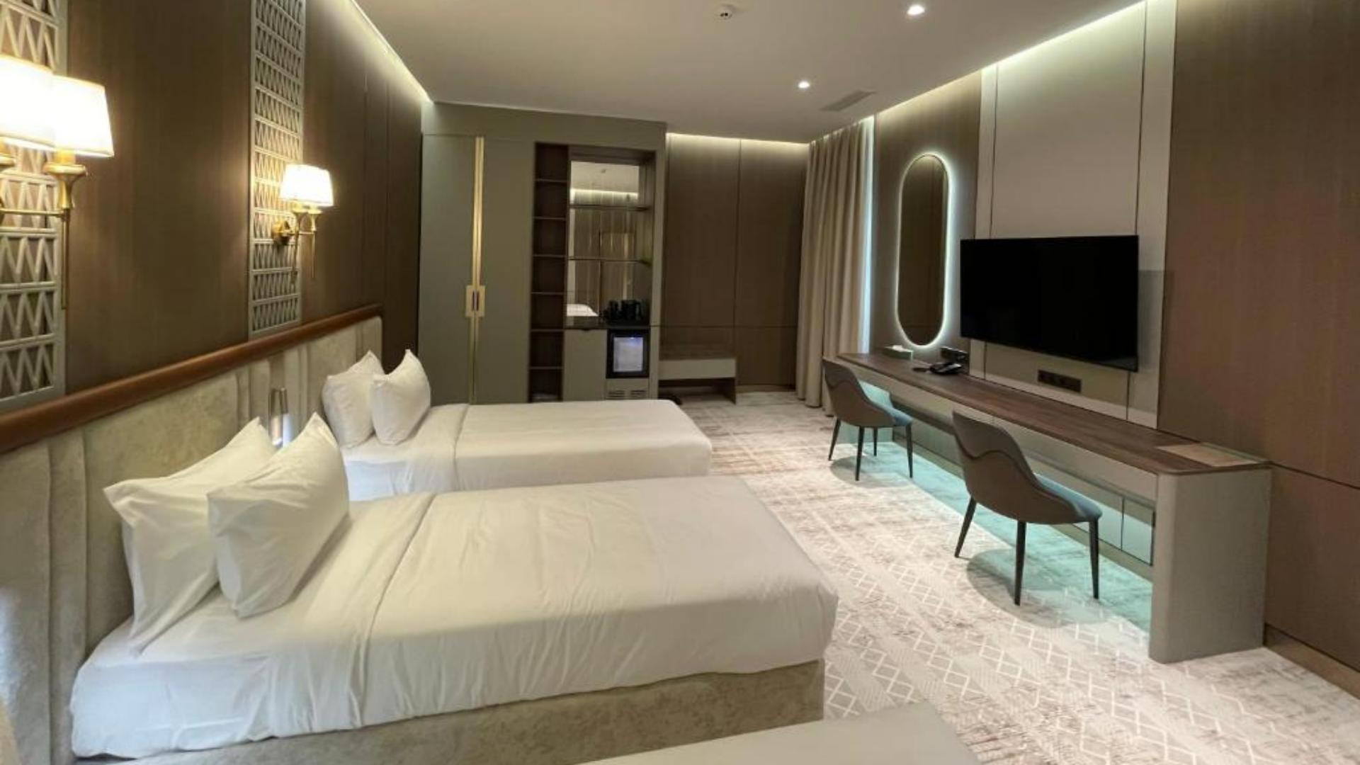 Modern hotel guestroom interior with crisp white bed linens on triple beds and contemporary room furniture.jpg