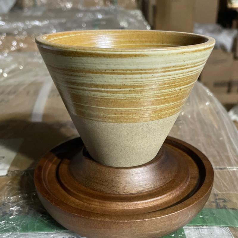 Hand-thrown tapered ceramic coffee cup with spiral glaze design resting on a custom solid wood saucer.JPG