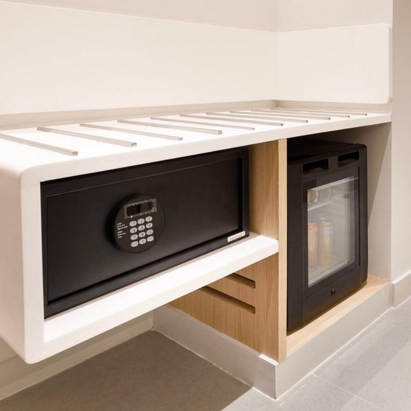 Black digital guestroom electronic safe box and silent mini bar fridge built into a modern wooden cabinet unit.jpg
