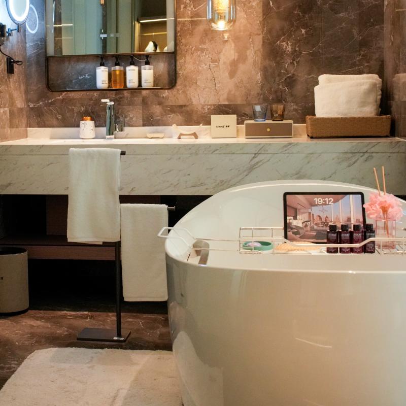 Luxurious hotel bathroom featuring plush white Taitang bath towels on display near a freestanding bathtub and marble vanity.JPG