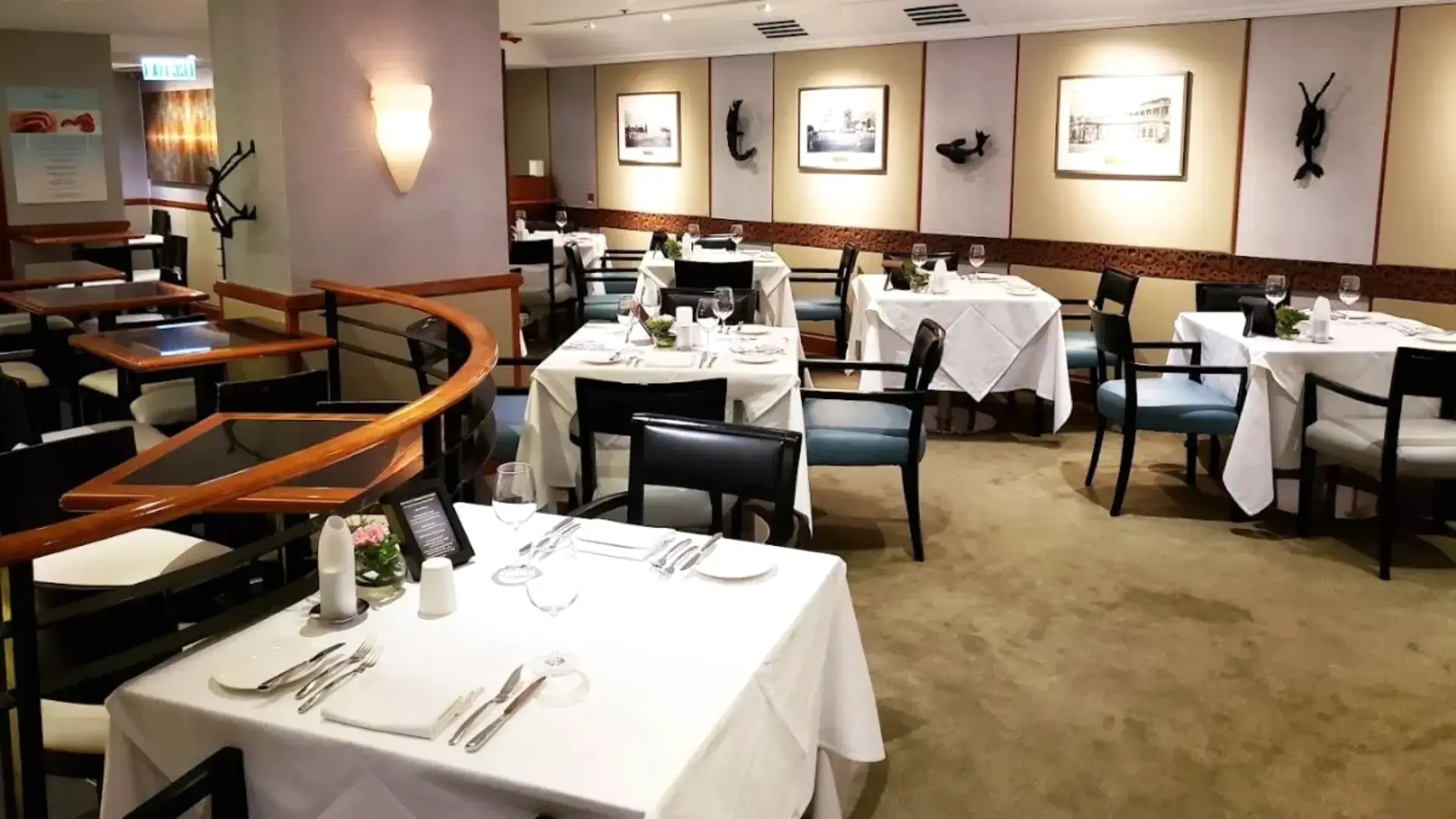 Spacious two-level main dining room featuring set tables with crisp white tablecloths and plush seating.webp