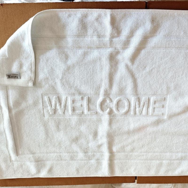 Pre-shipment inspection of white combed cotton hotel bath mat featuring embossed WELCOME jacquard lettering.jpg
