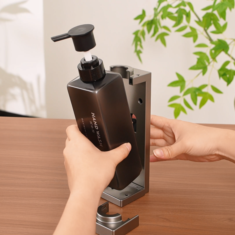 Staff inserting a refillable bulk amenity bottle into a Taitang lockable wall-mounted shower dispenser bracket.png