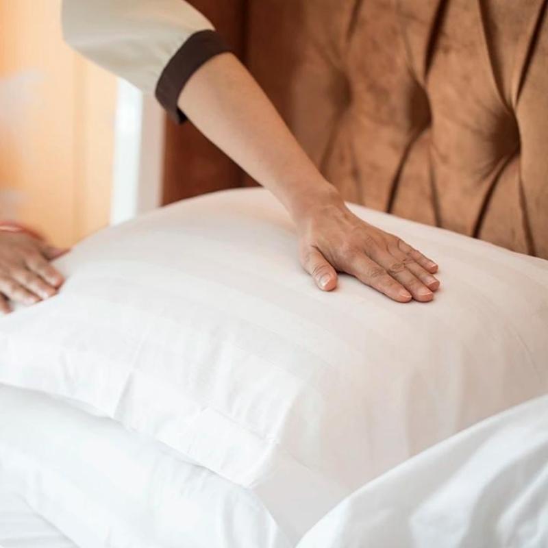 Hotel housekeeping professional arranging crisp white Taitang cotton sateen pillows on a luxury five-star hotel bed setup.jpg