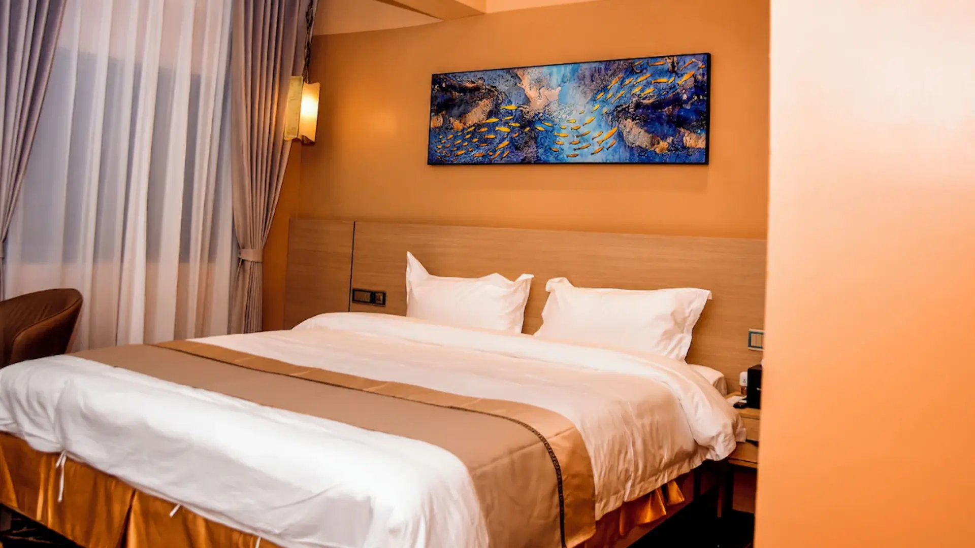 Cozy executive guestroom featuring styled bed linen, headboard lighting, and modern decor at Wealth International Hotel.webp