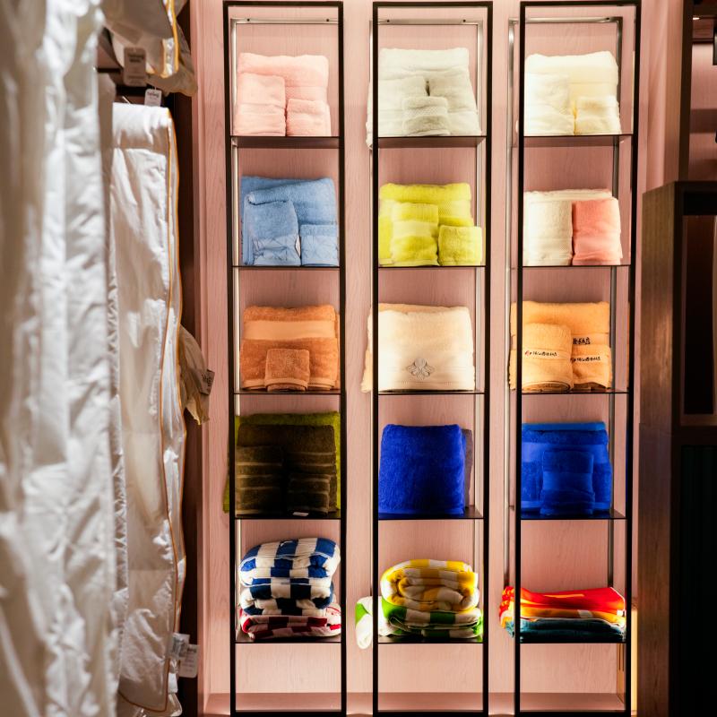 Neatly folded colorful wholesale hotel towels and luxury bath linens organized in modern illuminated showroom display racks.JPG