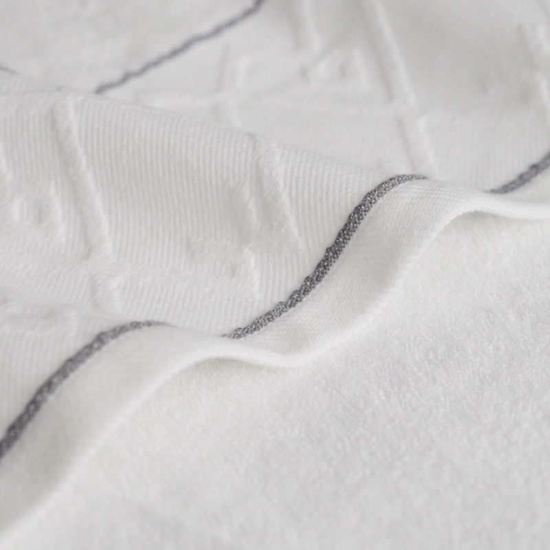 Close-up texture of high-GSM combed cotton hotel towel showing intricate jacquard weave and reinforced border stitching.png
