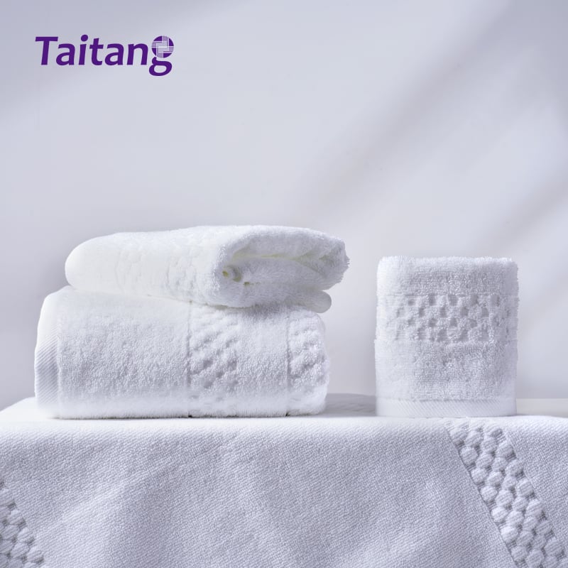 Folded jacquard hotel bathroom towels set showing clean pure white cotton texture.jpg