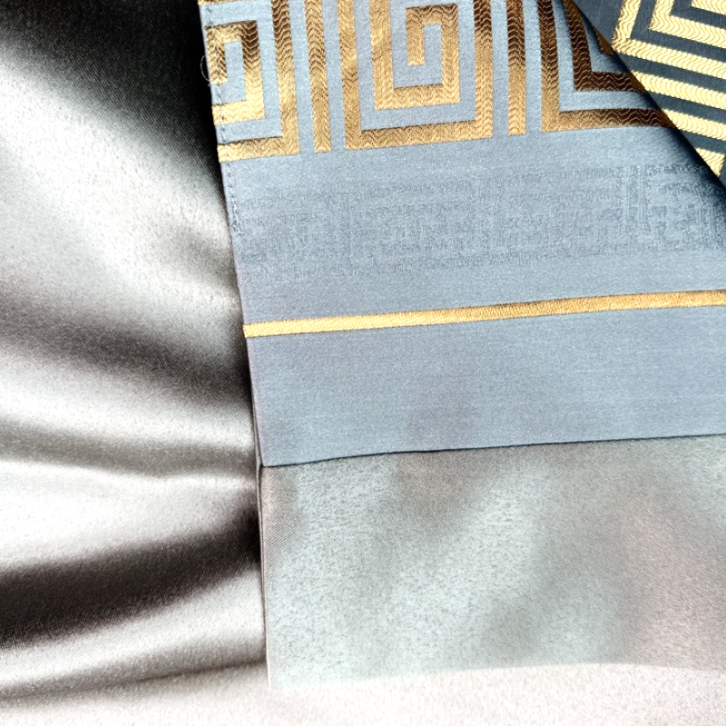 Detailed close-up of high-luster satin fabric with gold jacquard weave pattern for custom hotel textiles.png