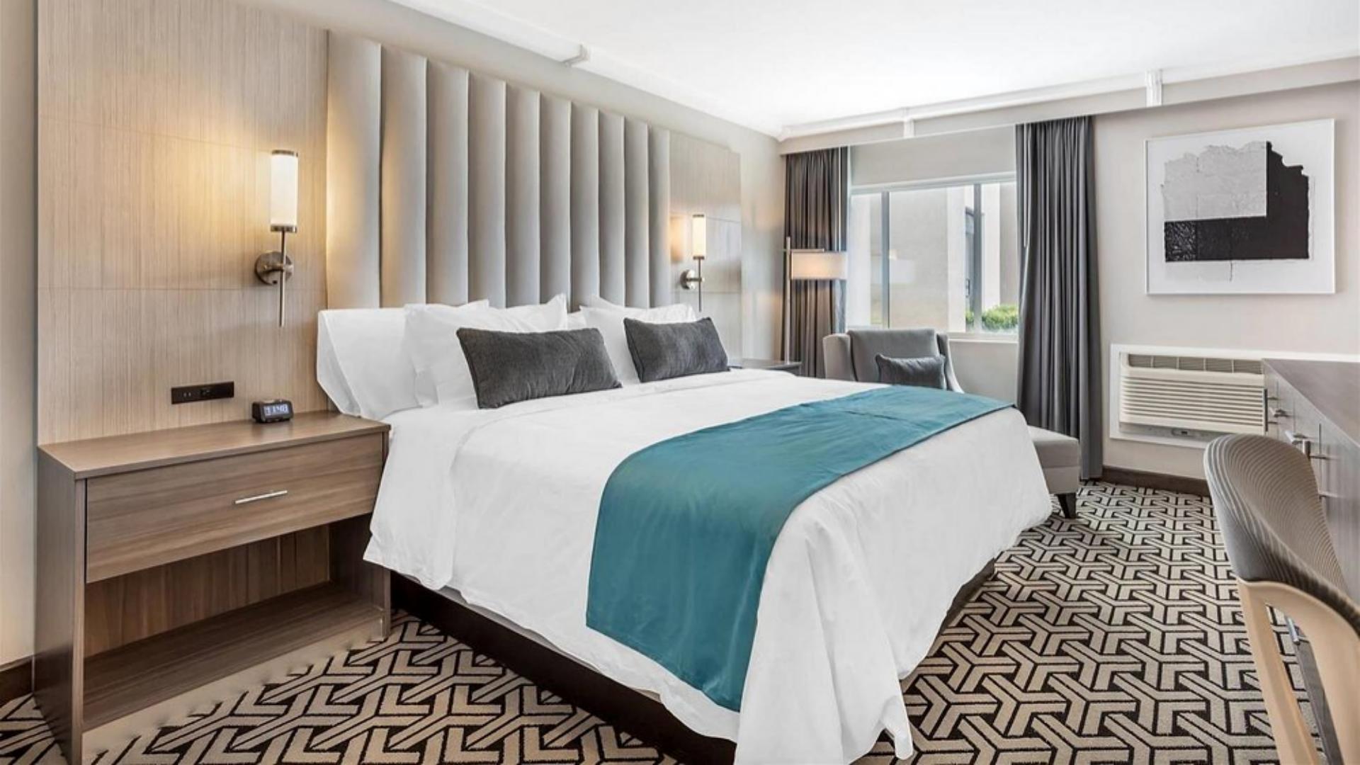 High-thread-count bed linens, plush pillows, and custom bed runners supplied by Taitang in a modern executive guestroom at The Ashi.jpg