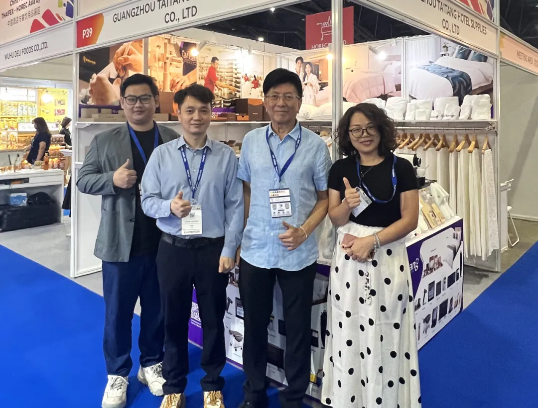 The Taitang executive team giving a thumbs up at their exhibition booth in Bangkok, showcasing the