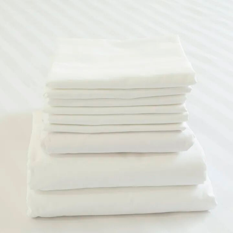Neat stack of freshly folded white hotel towels and linens, highlighting cleanliness and hygenic procurement standards.png