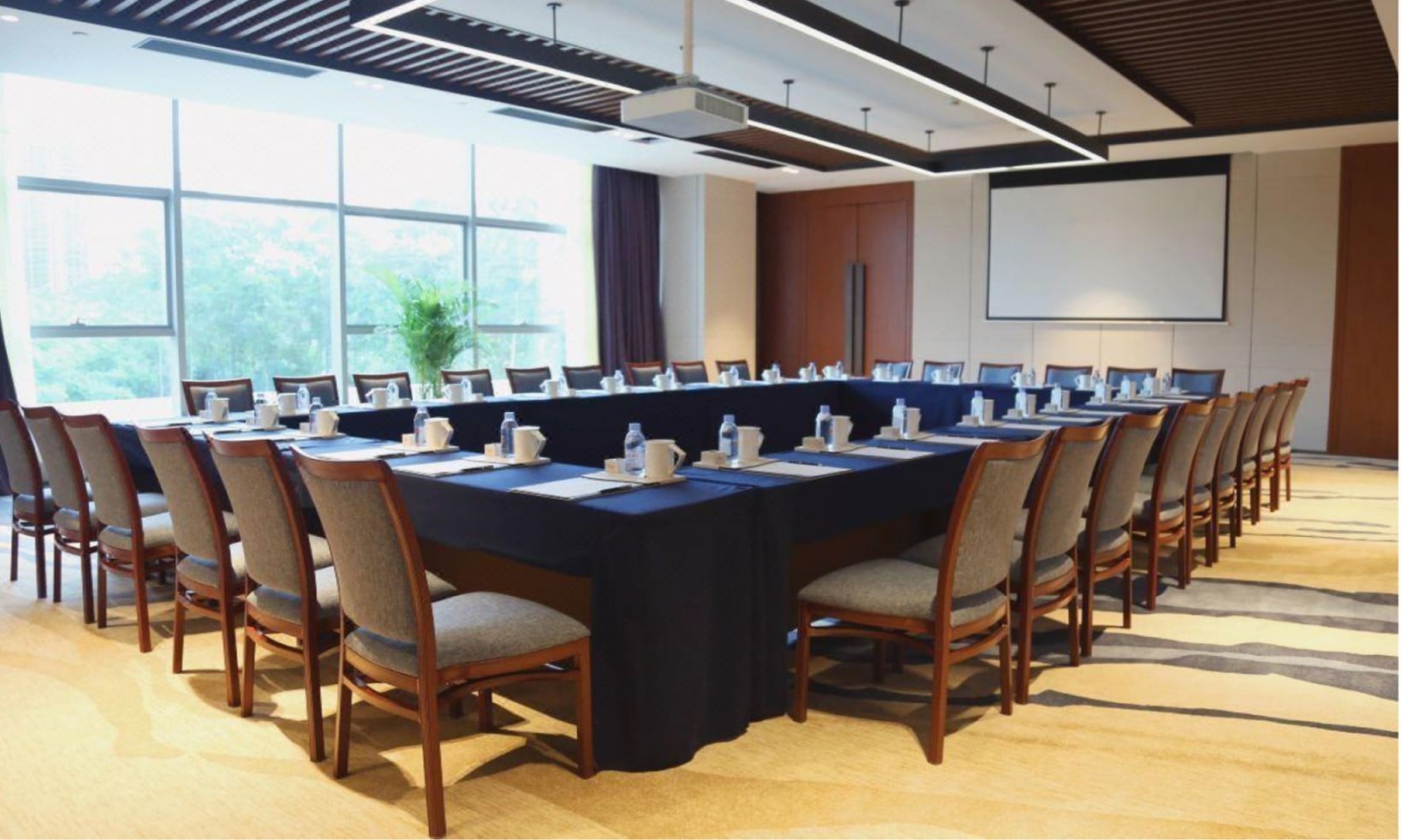 A detailed interior view of a professional conference and meeting room at the Wyndham Hot Spring Resort Nankun Mountain. Each place setting features ceramic tableware from Taitang, highlighting Taitang's role as a complete hotel supplies online solution.