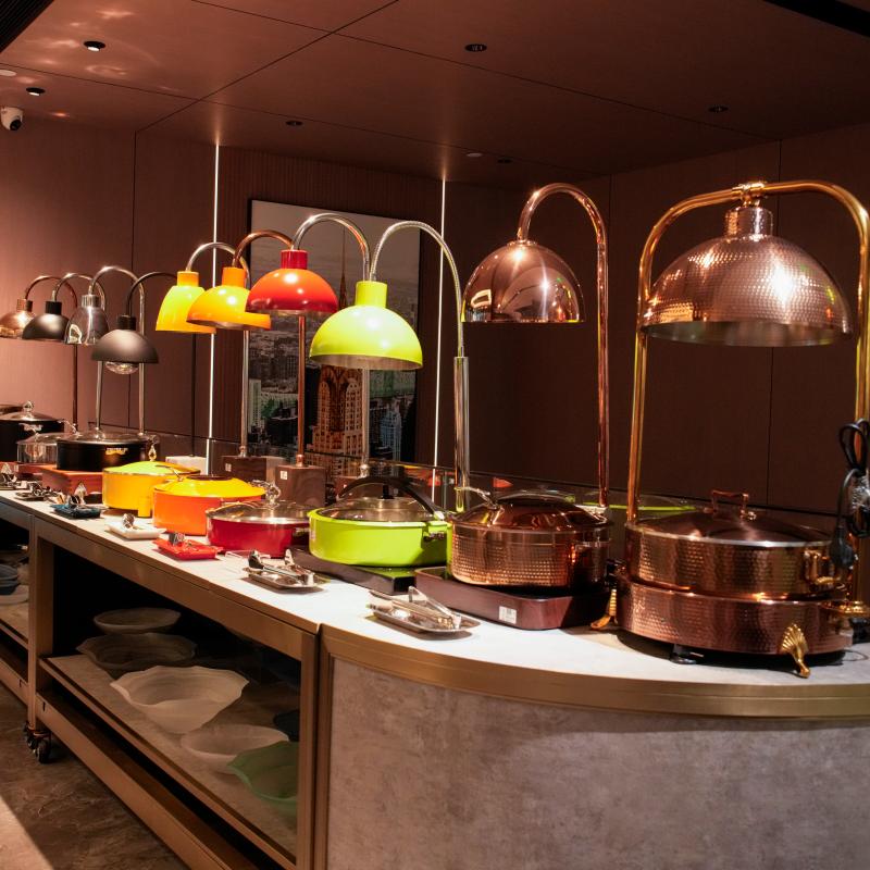 Close-up view of a professional Taitang hotel buffet counter station. Several high-end food warmer lamps (with colored and copper finishes) are active above various chafer dishes.JPG