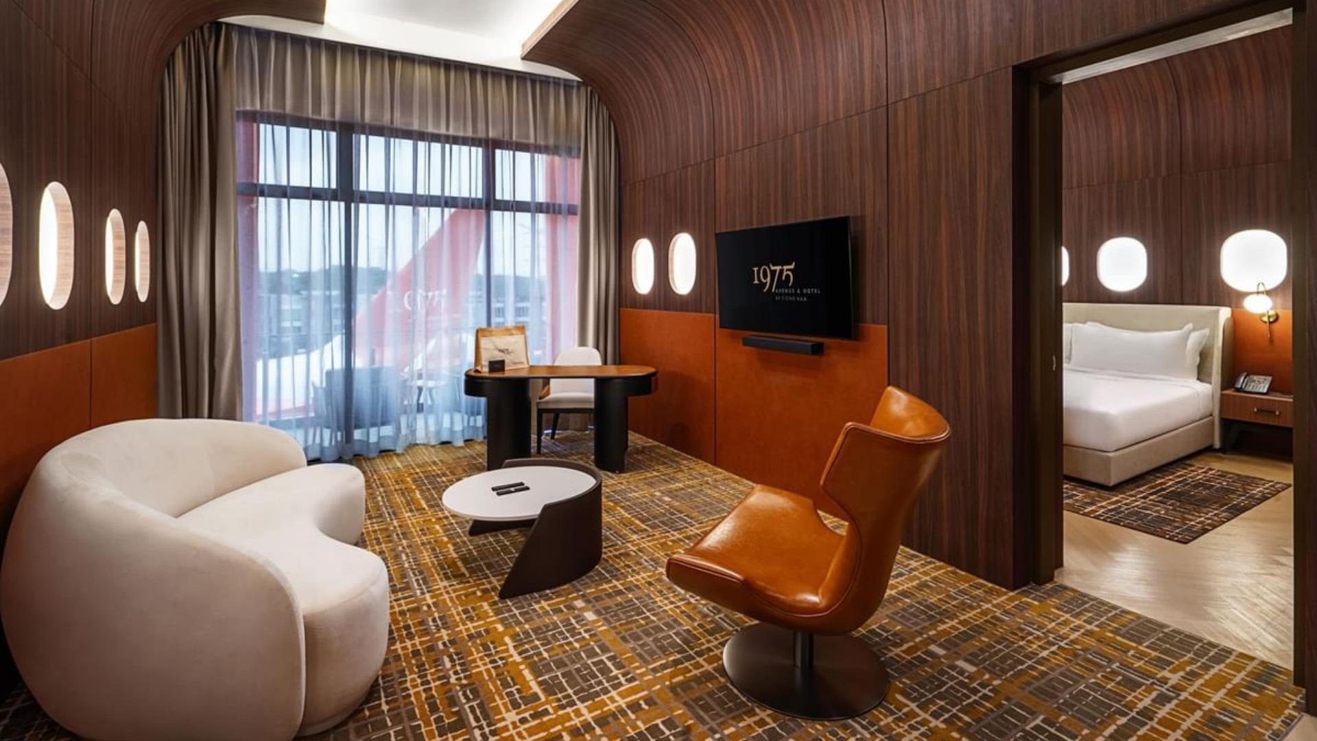 Luxury aircraft suite living room interior with a curved white sofa, leather lounge chair, and wood wall paneling.jpg