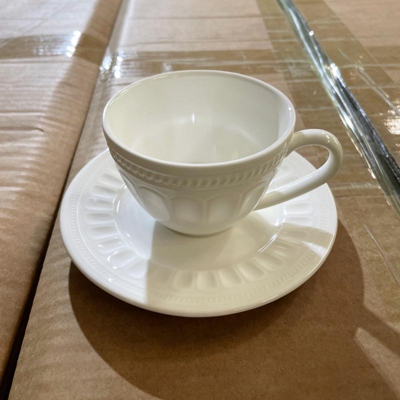 White embossed bone china teacup and matching saucer displayed on shipping packaging prior to dispatch.JPG