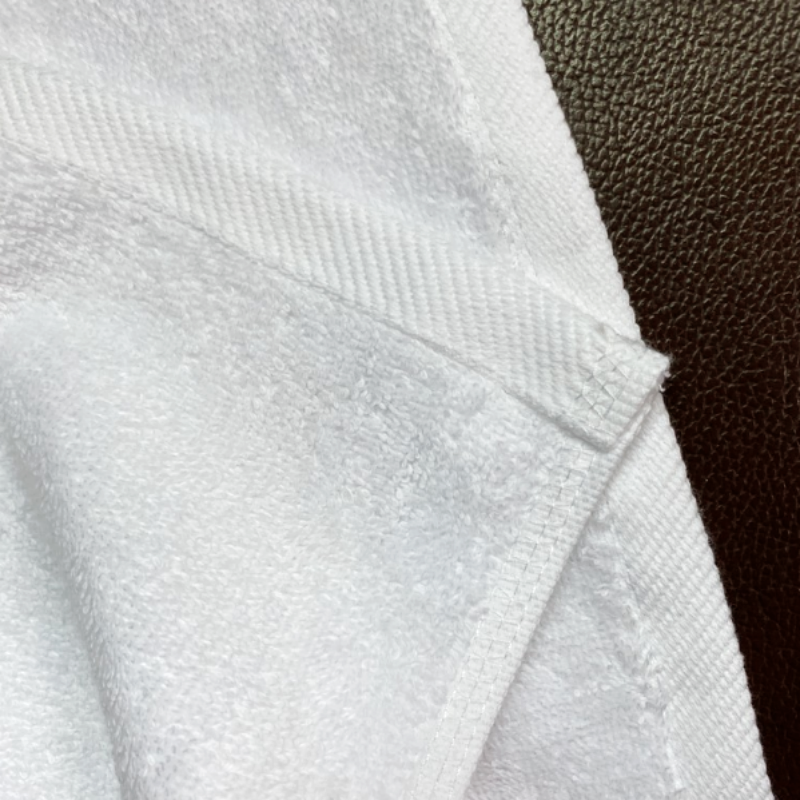 Close-up detail of double-stitched hem and heavy-duty terry weave on white hotel bath linen.png