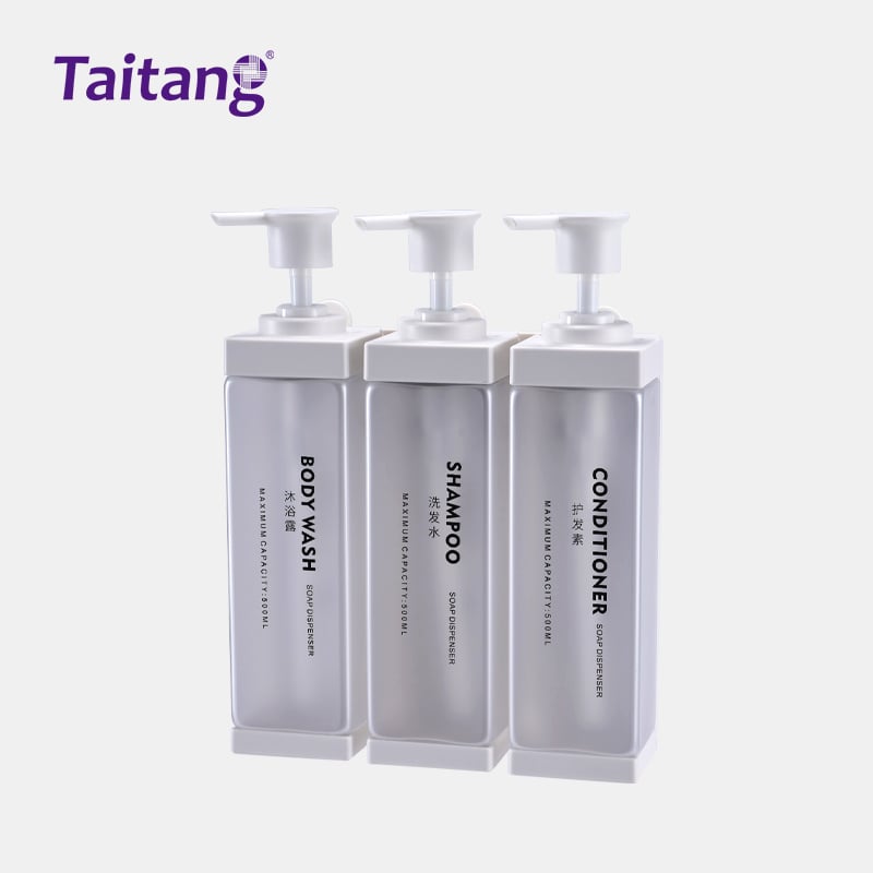 Triple-chamber white translucent Taitang commercial shampoo dispenser bottles inside a white mounting wall bracket.jpg
