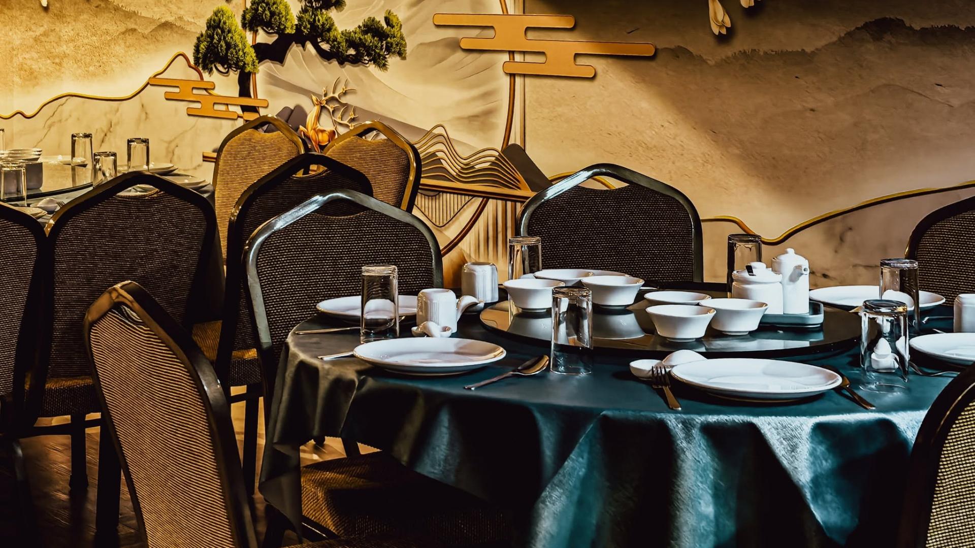 Traditional Chinese restaurant private dining room setup with round banquet tables, green tablecloths, and ceramic tableware.jpg