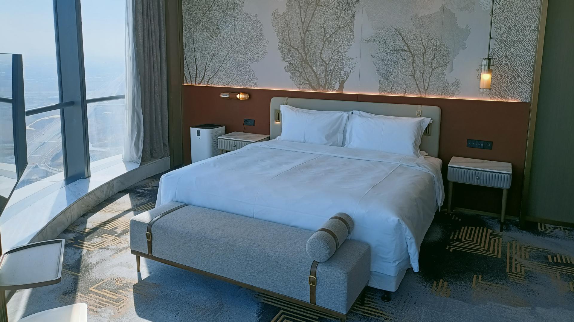 Custom hotel furniture by Taitang including a upholstered headboard, wooden nightstands, and bed bench in a luxury suite at Wyndham Grand..jpg