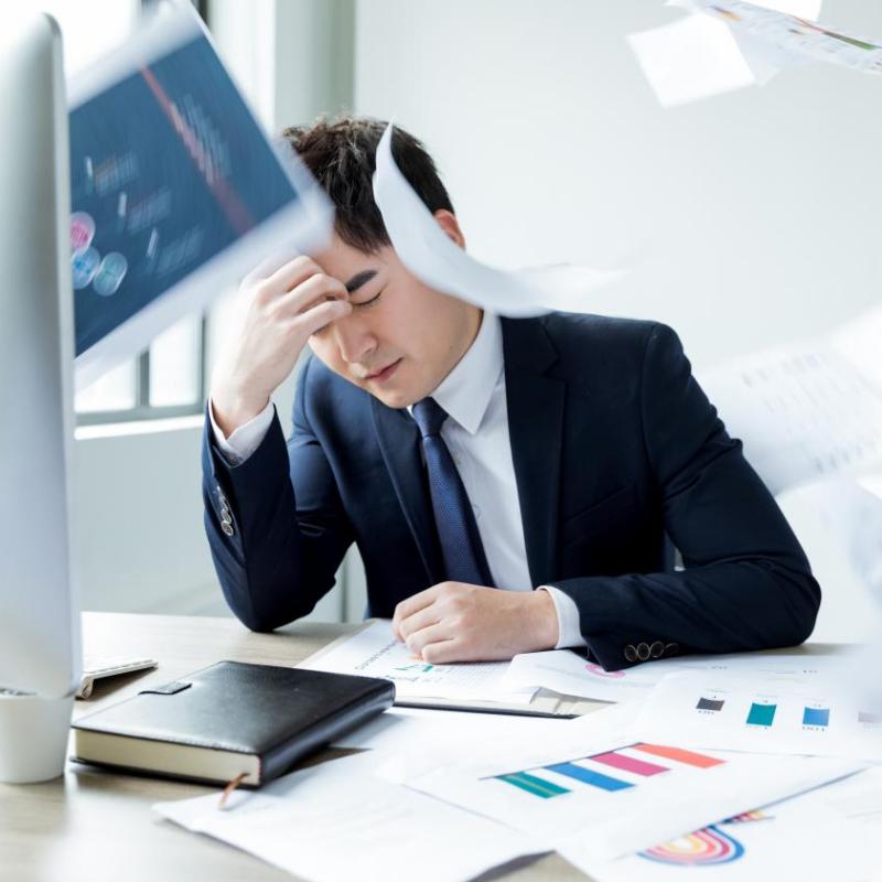 Stressed business professional overwhelmed by multiple vendor documents, highlighting procurement challenges solved by Taitang integrated supply solutions.jpg