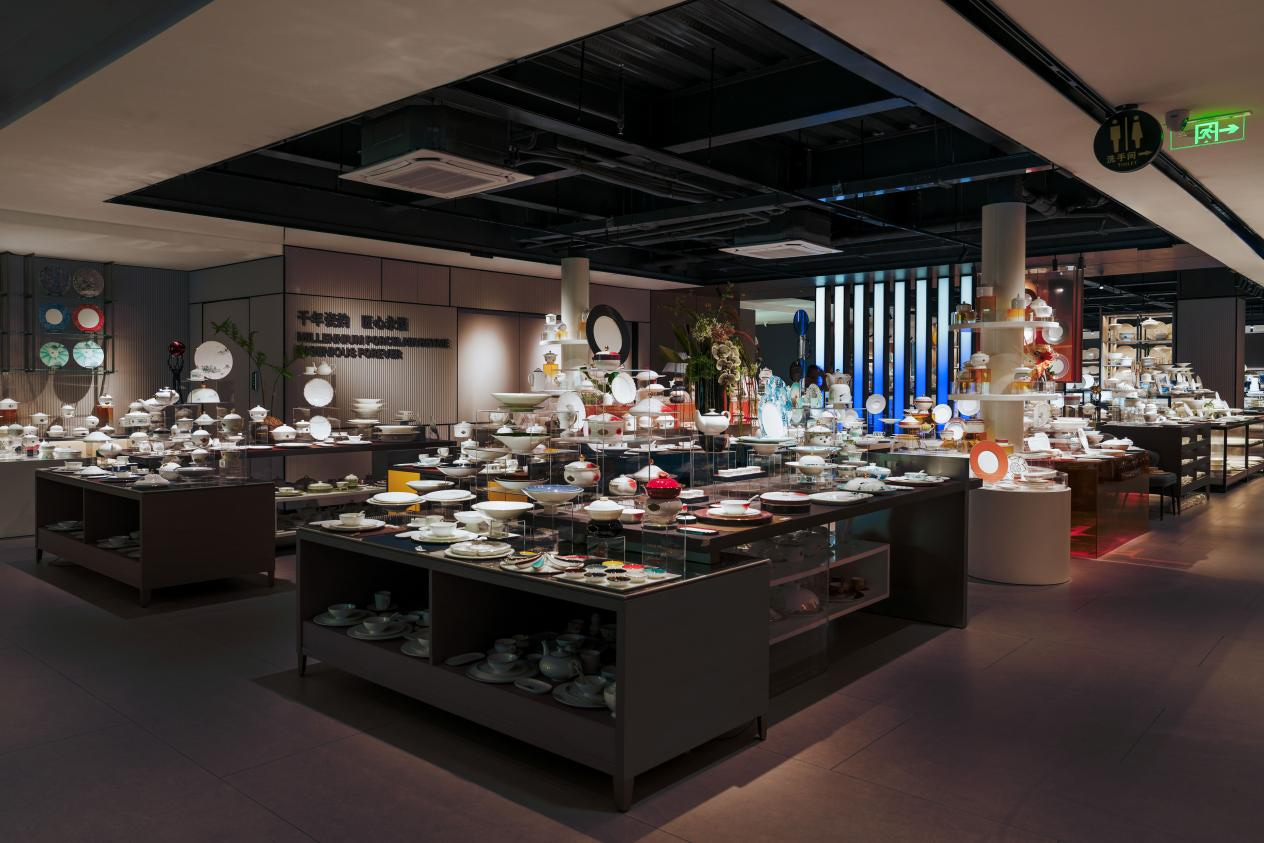 An expansive luxury showroom displaying a wide collection of professional hotel tableware, porcelain sets, and fine dining ceramics organized on modern black display tables.
